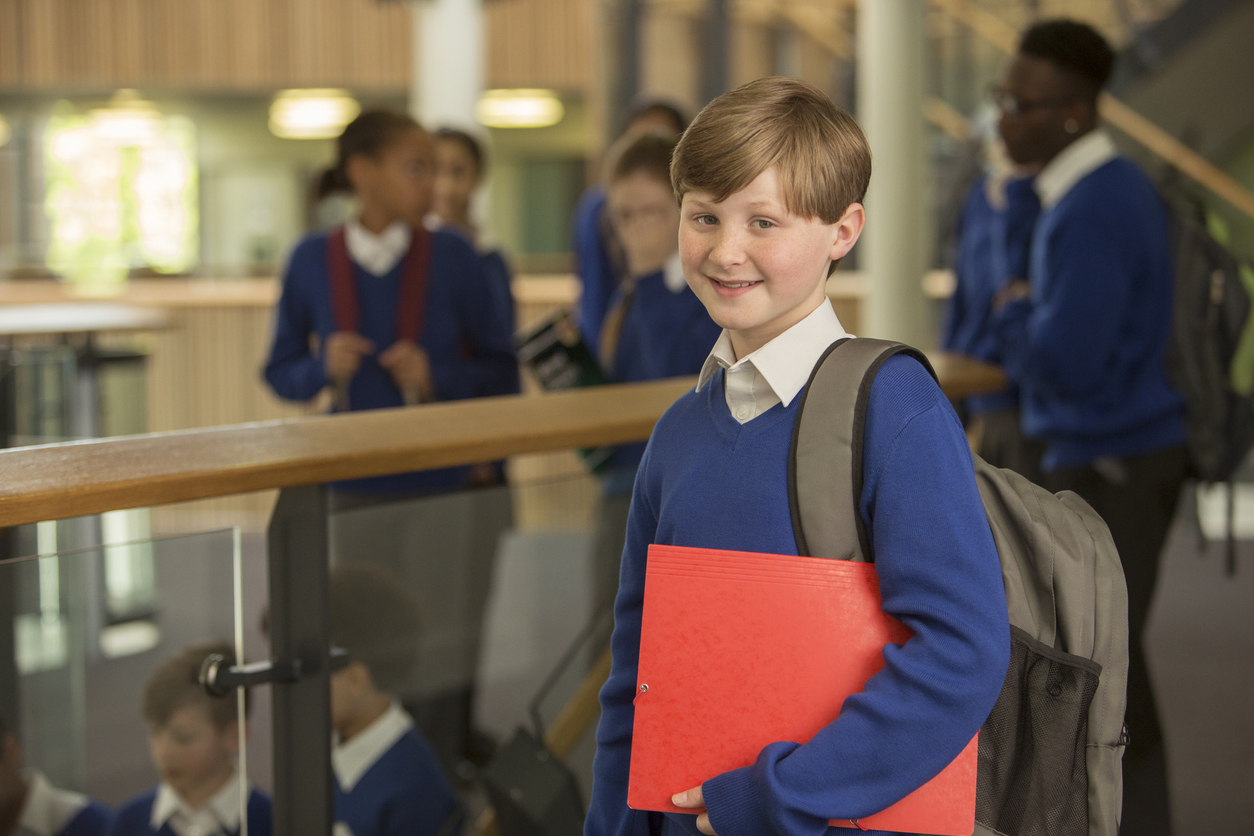 Schoolboy in blue uniform holding a red folder