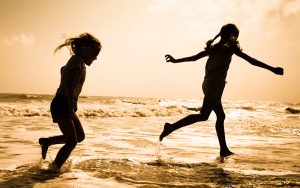 Children play in the sea at sunset