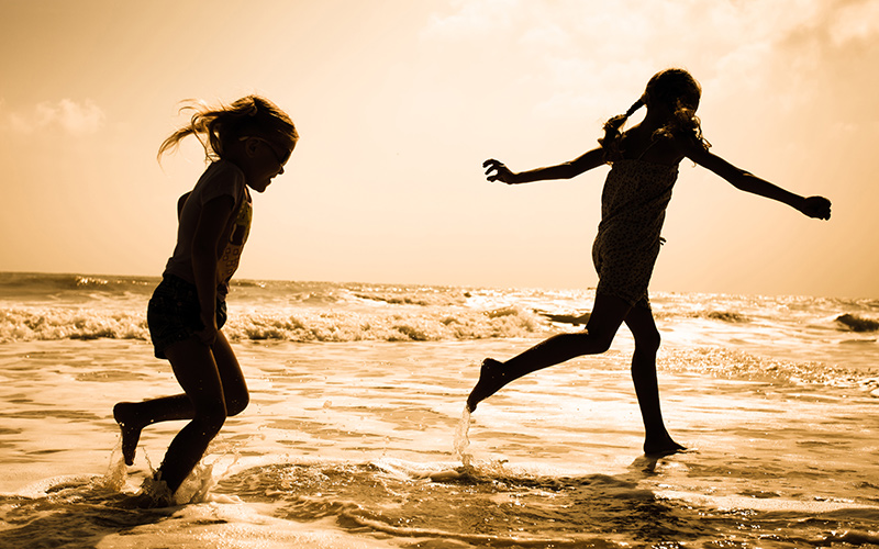 Children play in the sea at sunset