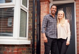 A male and female couple standing on their doorstep