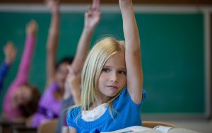 School girl raises hand in class