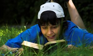 Teenage boy reads in the park