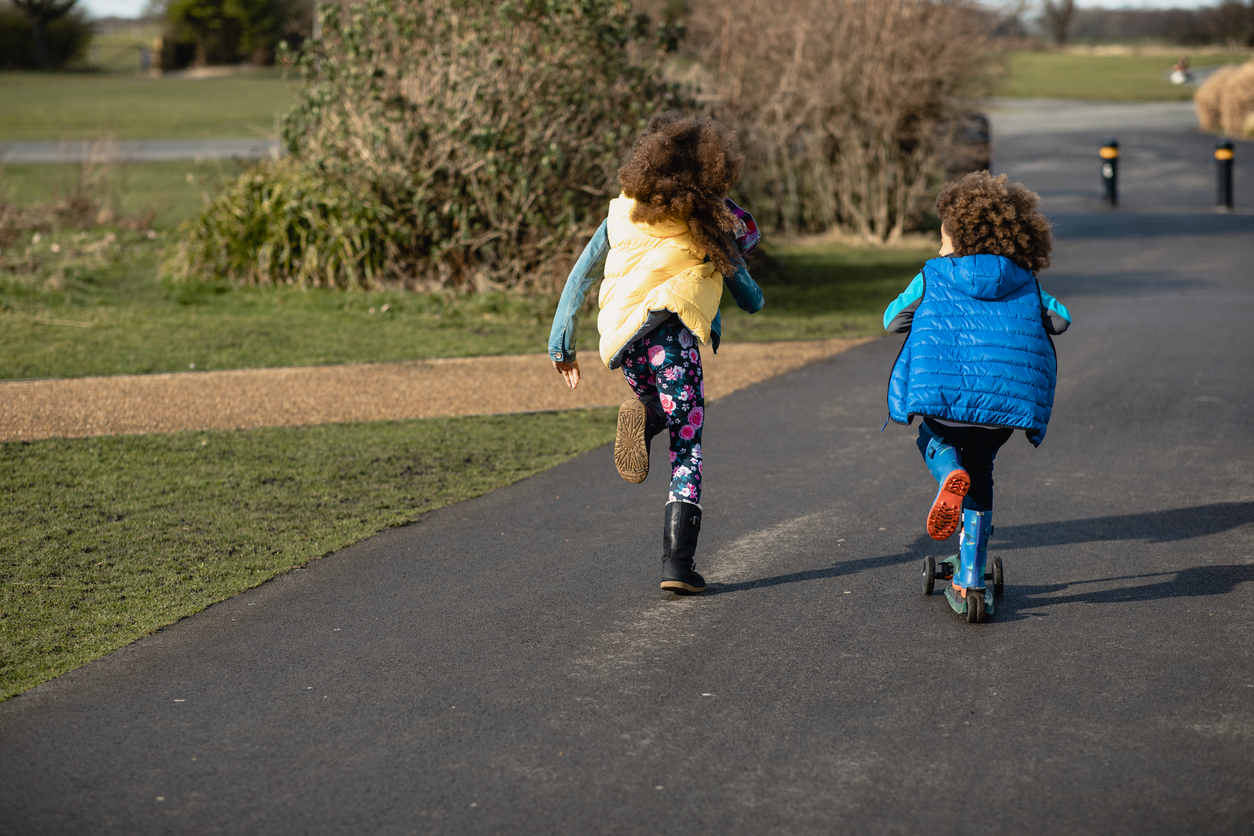 Two siblings running, shown from behind