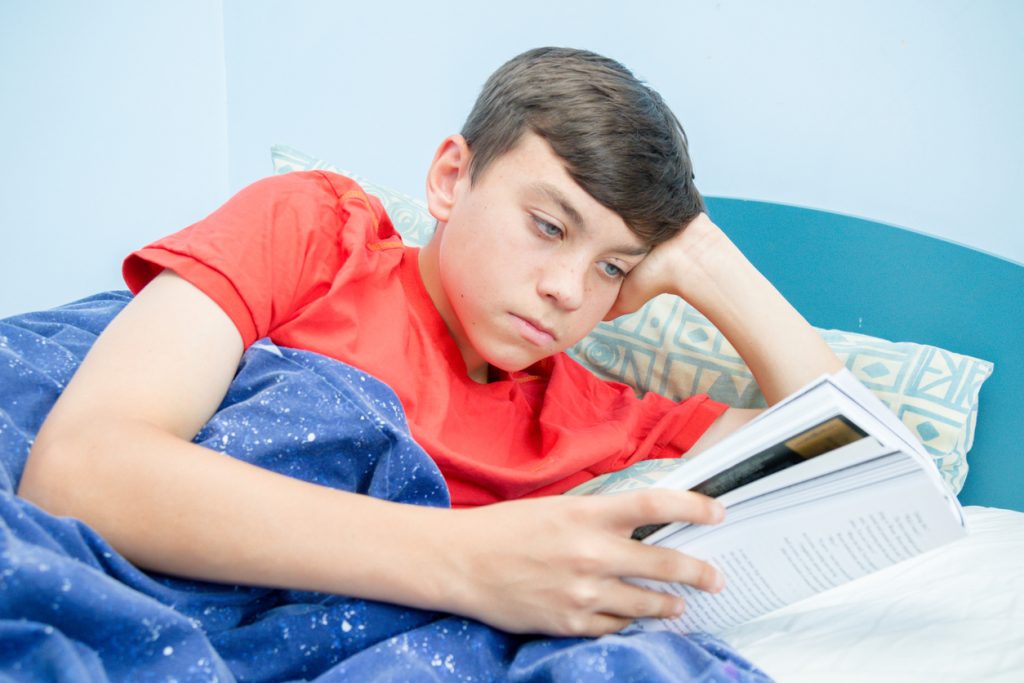 Boy in red tshirt reading a book