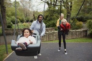 Two mothers pushing children in swing