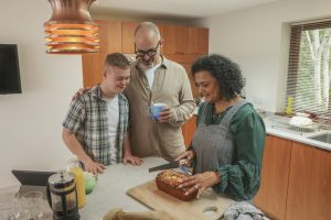 Mature deaf parents and adult son with down syndrome looking at freshly baked cake in kitchen