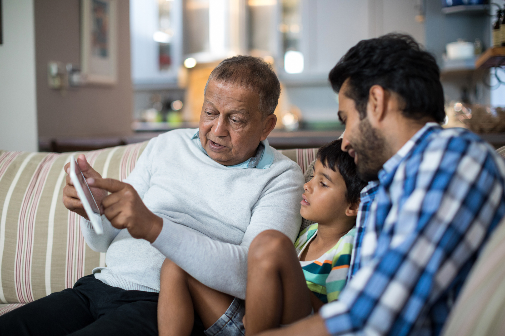 Three generations of family using ipad on the sofa