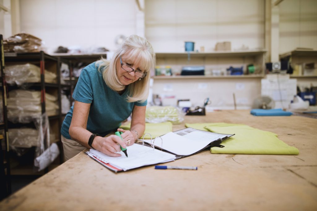 Woman in her sixties writing in a notebook at work