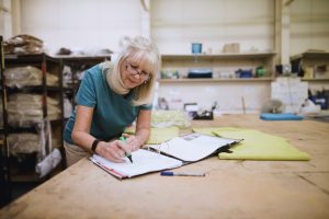 Woman in her sixties writing in a notebook at work