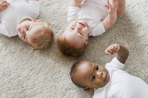 Three babies lying on the carpet