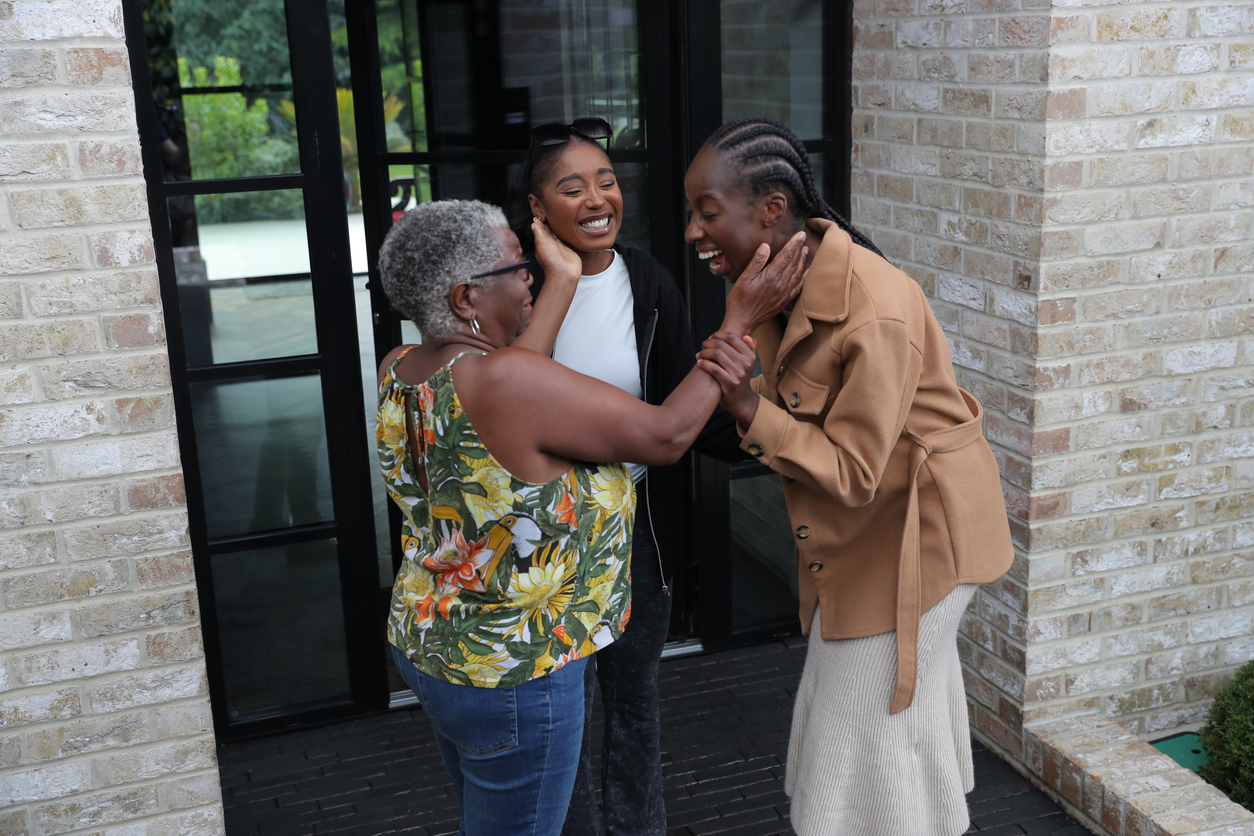 Mother and two adult daughters in front of doors to grey building