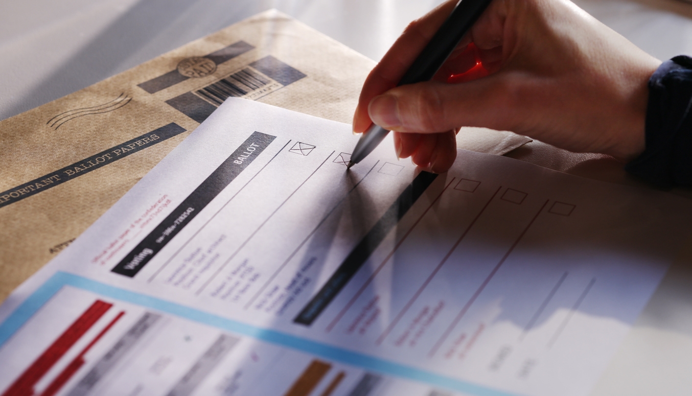 A hand filling in a ballot paper