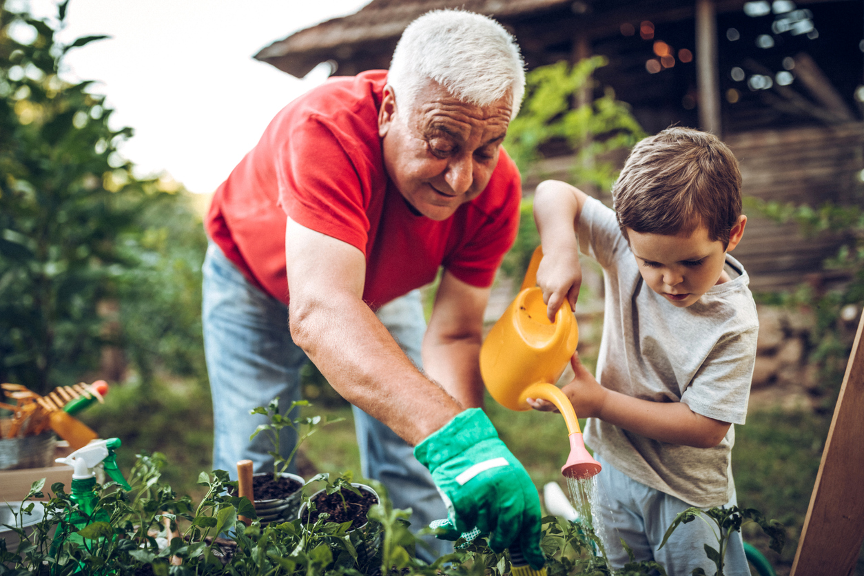 Man and grandson watering plants in the garden