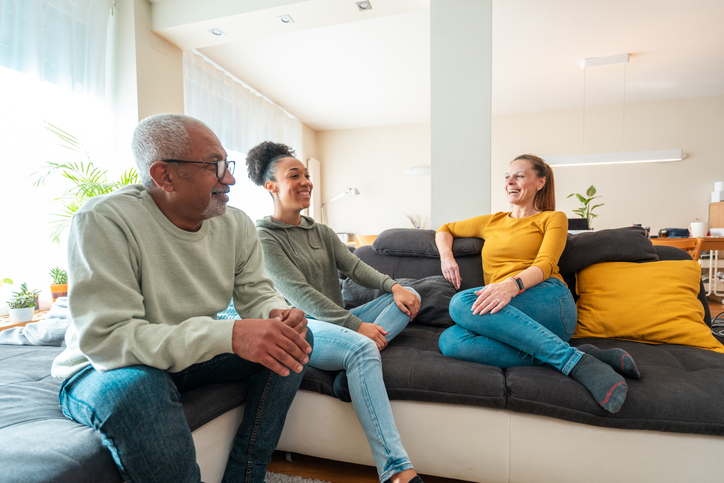 Adult children and parent on sofa at home