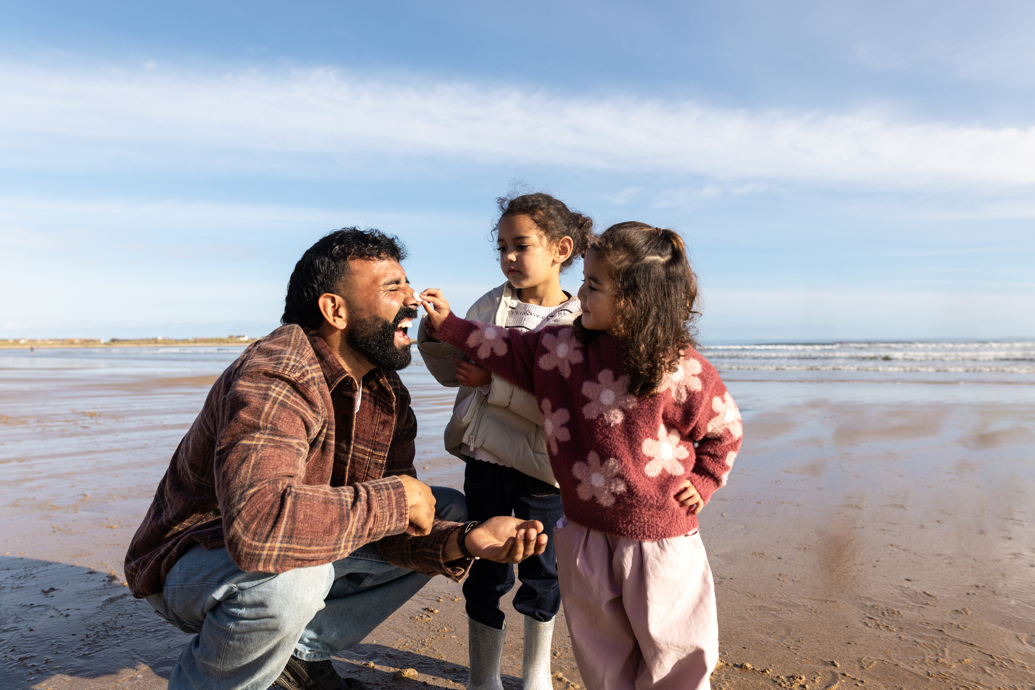 Young dad with daughters on the beach