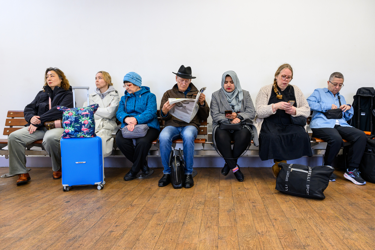 A line of people sitting on chairs in a waiting room