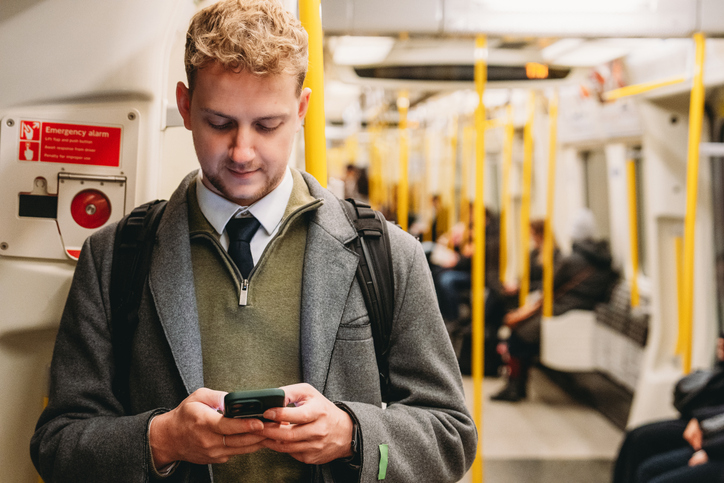 Young man looking at phone while on the Tube